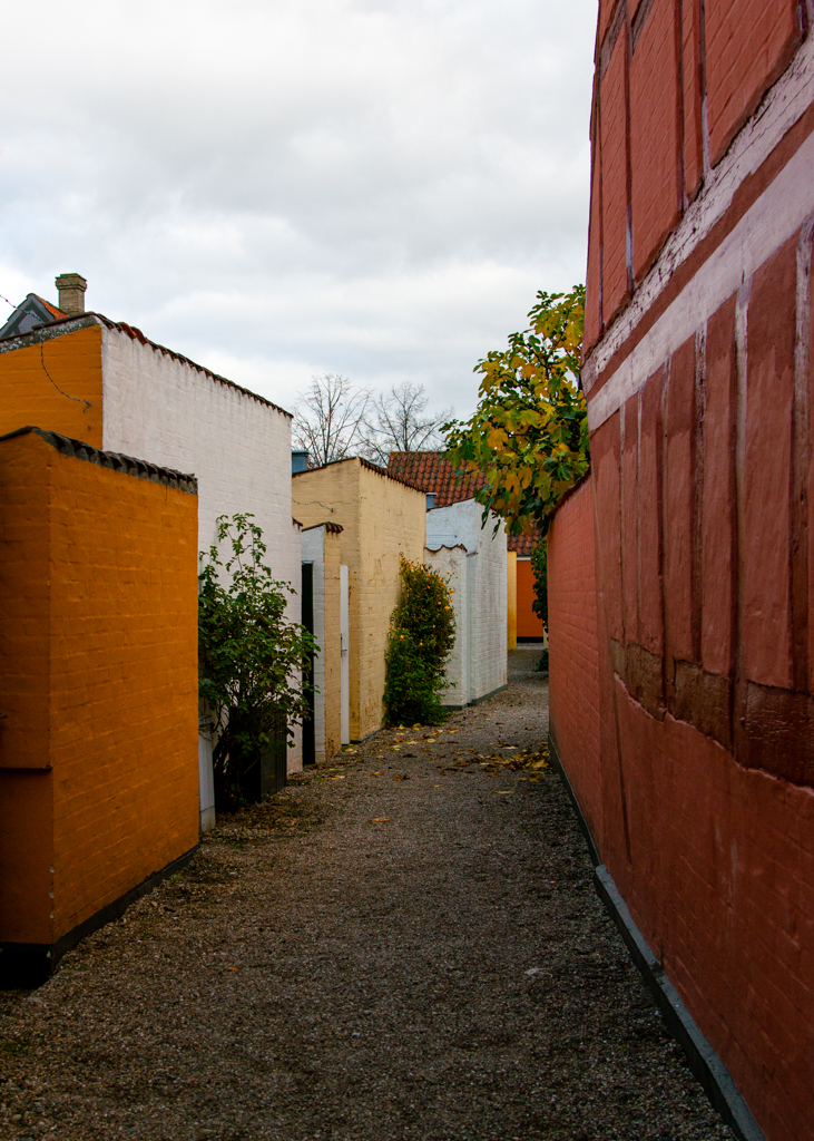 A back alley with colourful brick walls in brigh yellow, light yellow, white and terra cotta.
