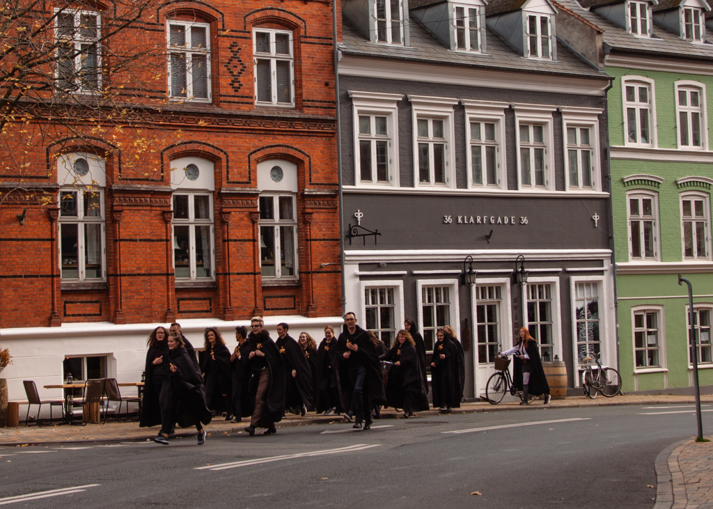 Young adults walking on the street in Odense dressed in black robes, like Hogwart students.