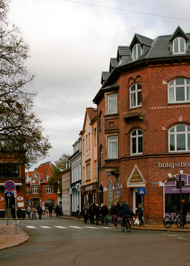 A photo of a street intersection filled with pedestrians and a cyclist on the road.