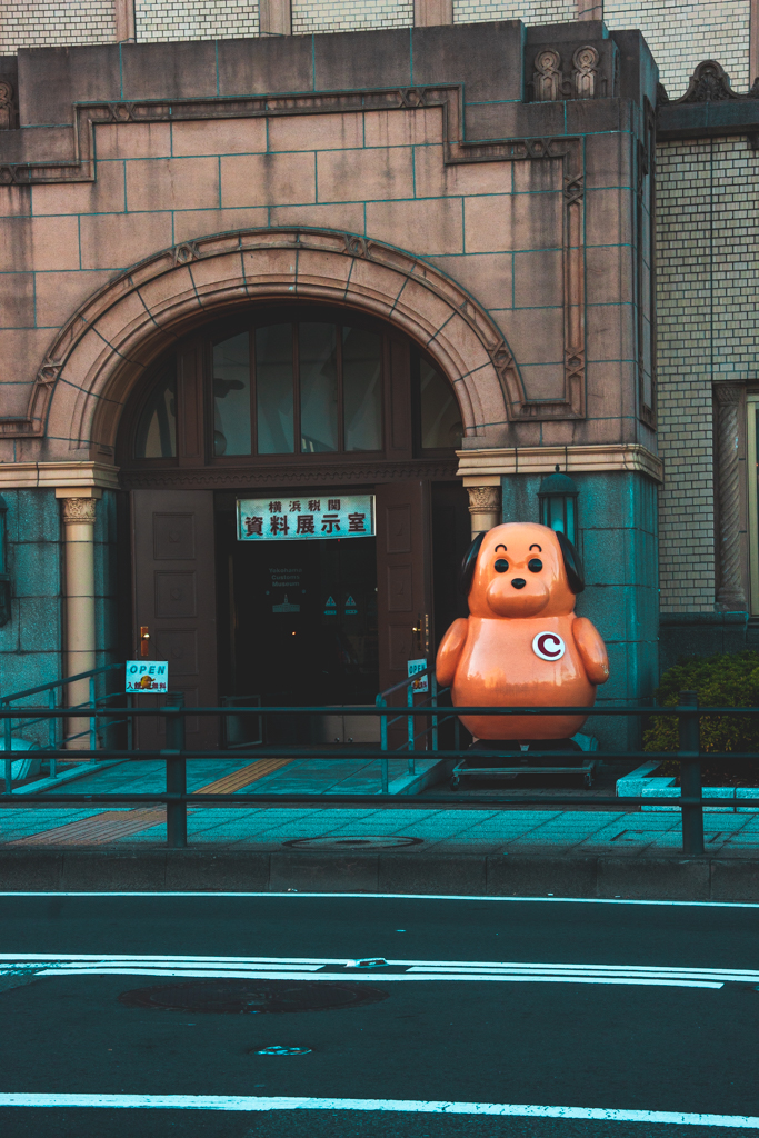 The entrance of a post office across the street with a cartoon dog statue by the ramp.