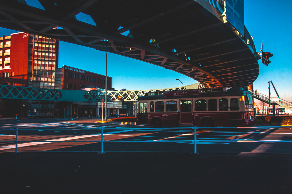 A streetcar in Yokohama passing the crosswalk under a circular bridge.